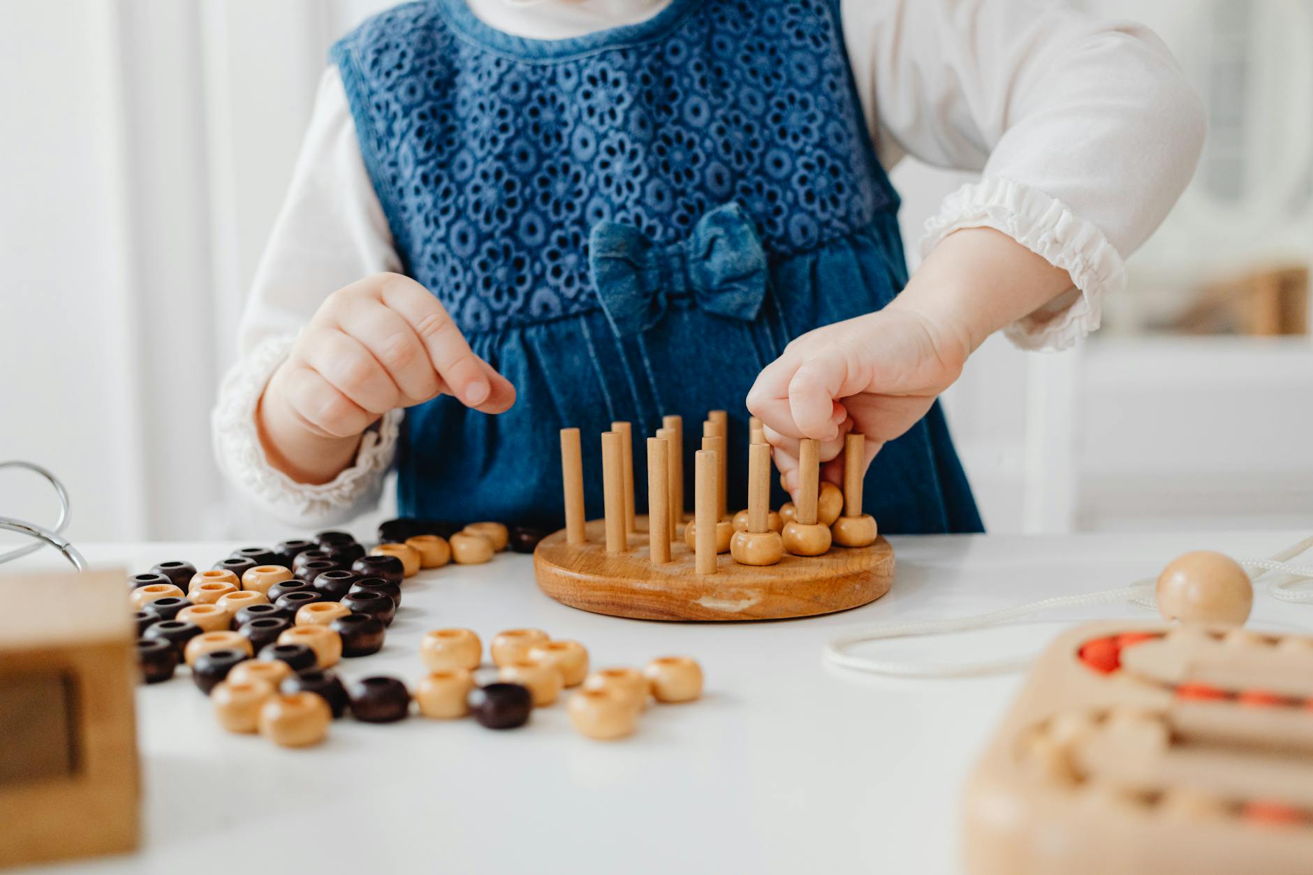 https://www.pexels.com/photo/a-person-in-white-long-sleeves-holding-a-wooden-toys-on-the-table-7296764/
